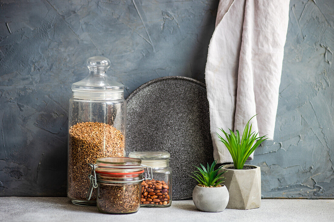 Rohkostzutaten in Glasgefäßen, Zimmerpflanzen in Zementtöpfen auf Küchenarbeitsplatte
