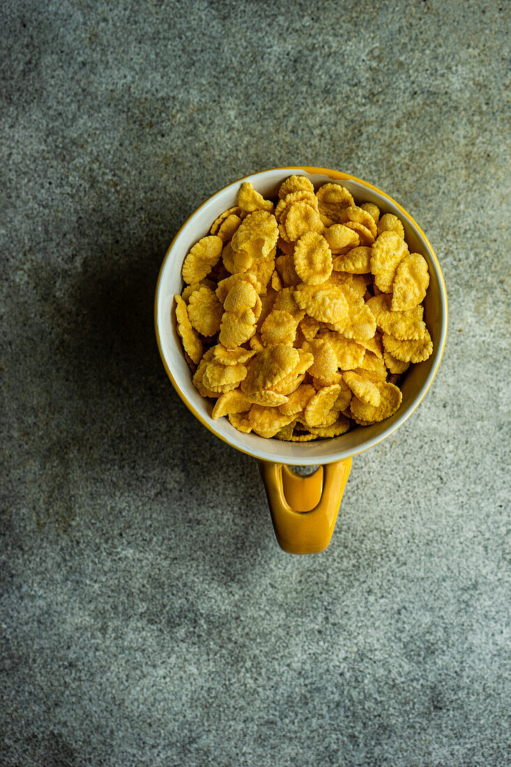 Bowl full of corn flakes on concrete table background
