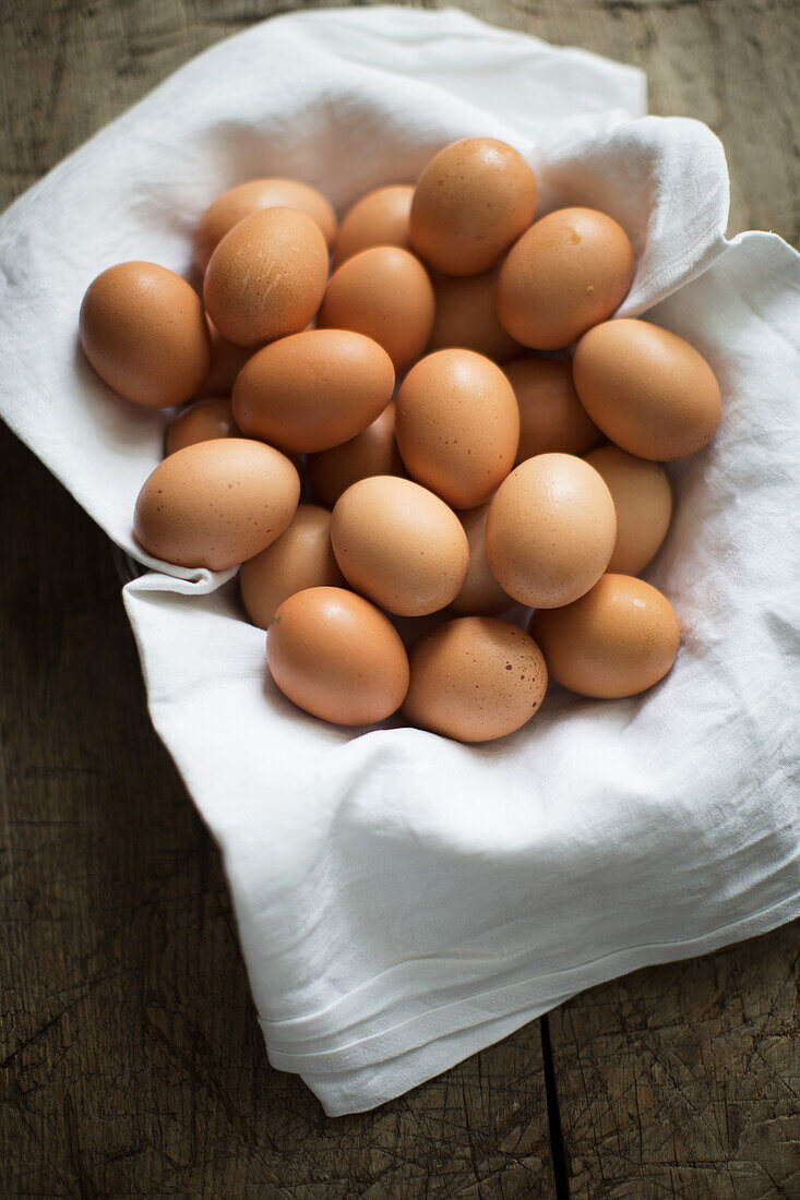 Fresh brown eggs in a basket with a white cloth