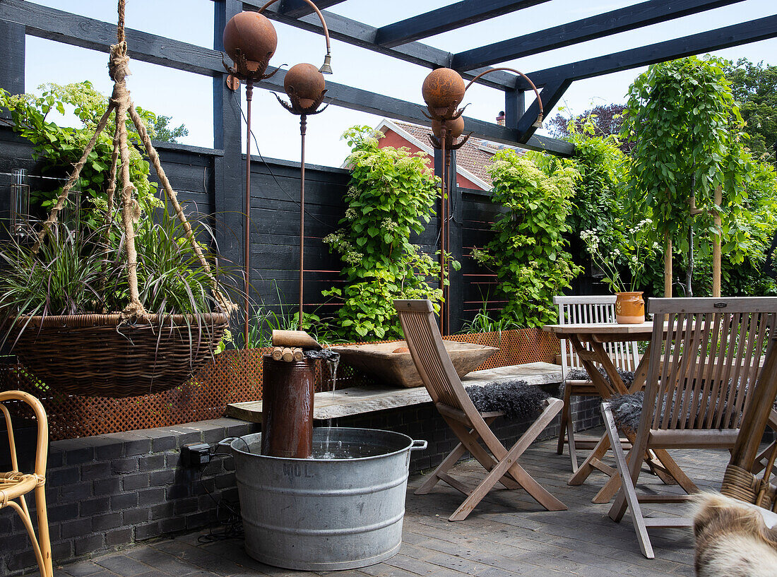Sitzplatz, bepflanzter Hängekorb und rostige Dekoration auf der Terrasse