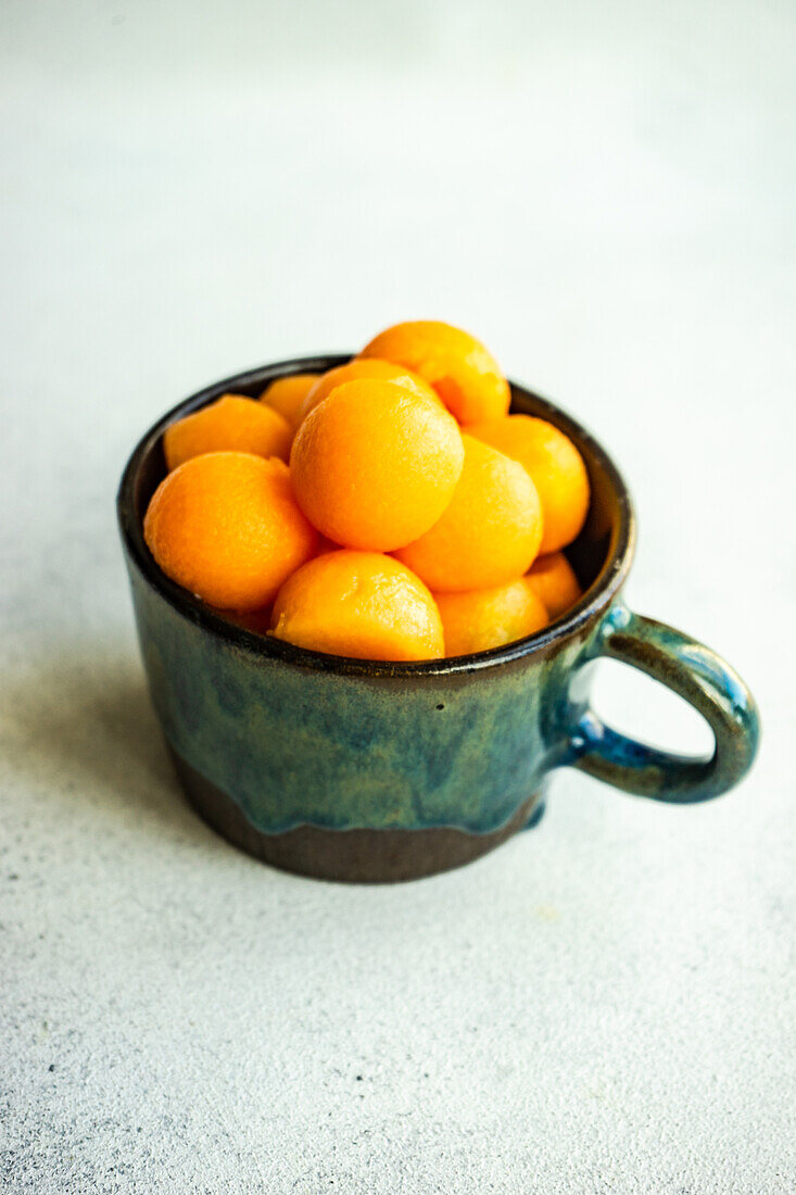 Balls of ripe cantaloupe melon in the ceramic cup on concrete table for dessert meal