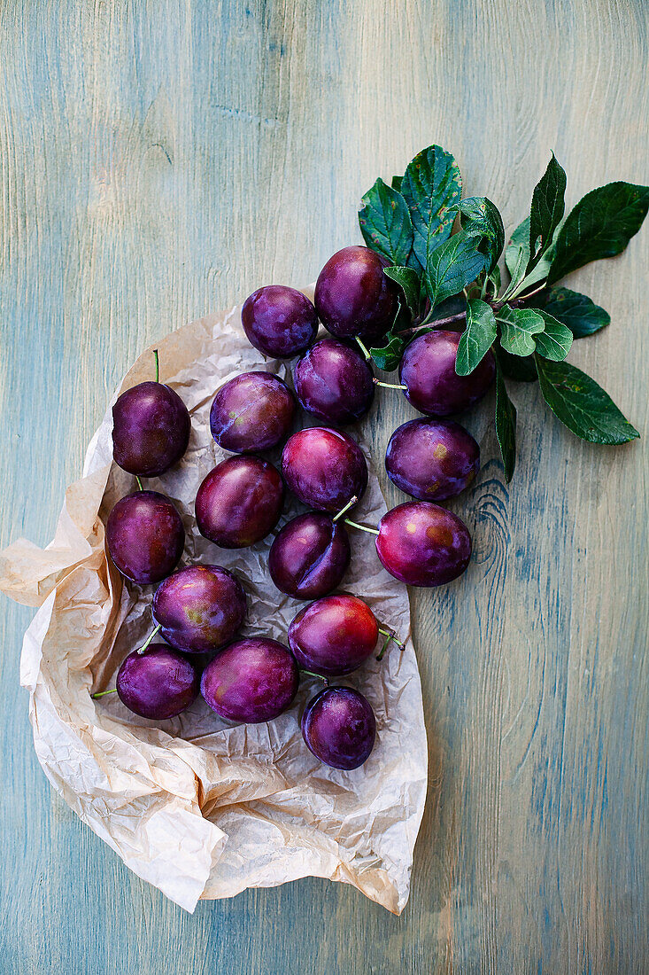 Plums with leaves on a wooden background