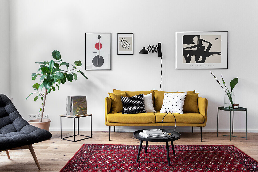 Senfgelbes Sofa und Beistelltische unter moderner Kunst und Ficus im Wohnzimmer