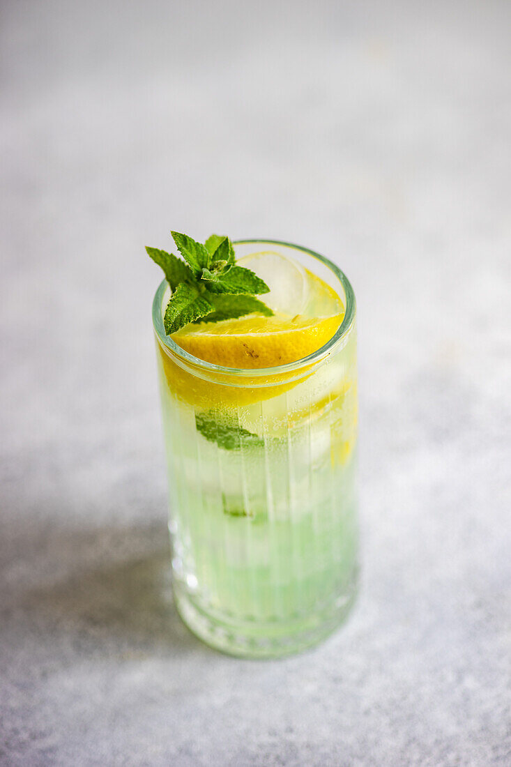 Mojito cocktail with mint and lemon, served in a crystal glass on a concrete table