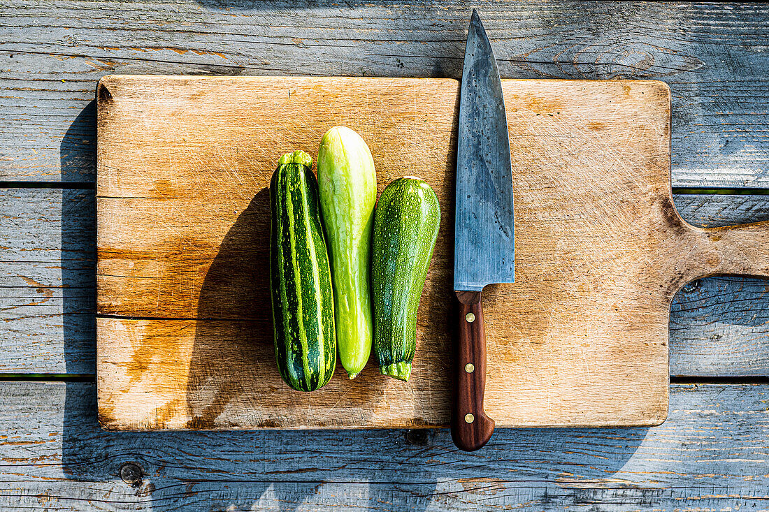 Zucchini with a knife on wooden cutting board