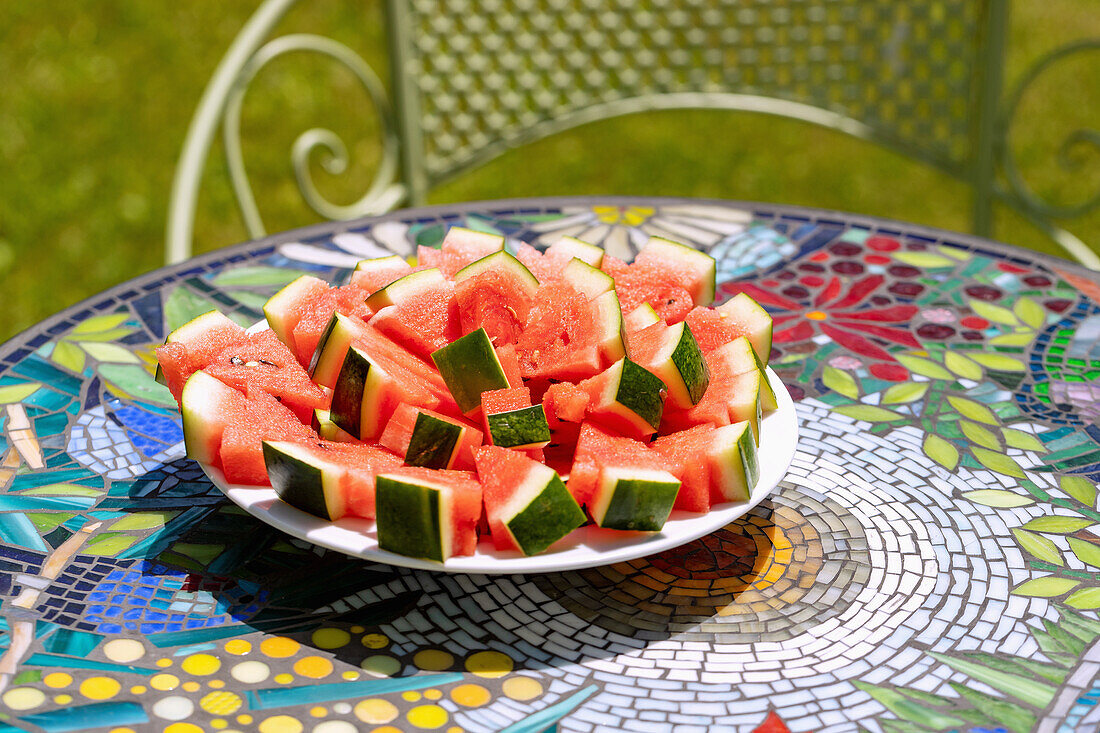 Plate with watermelon pieces on a mosaic table in the garden