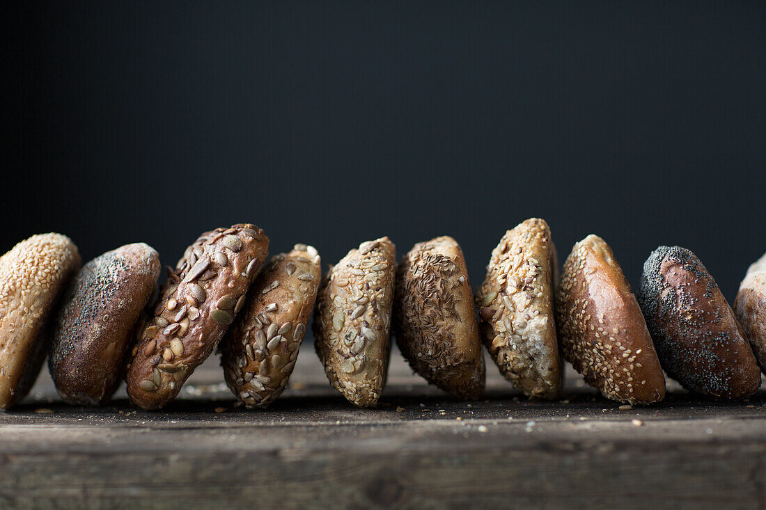 Viele verschiedene Körnerbrötchen vor schwarzem Hintergrund