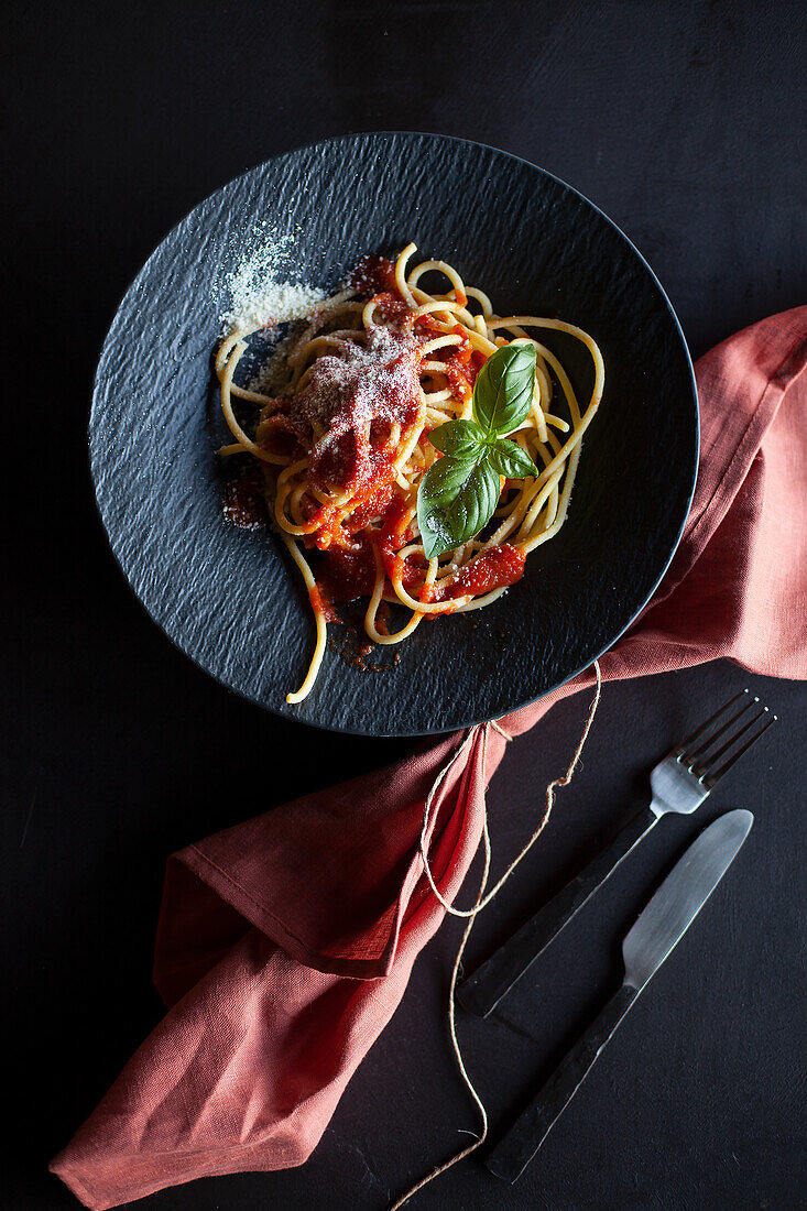 Spaghetti with tomato sauce on a black plate