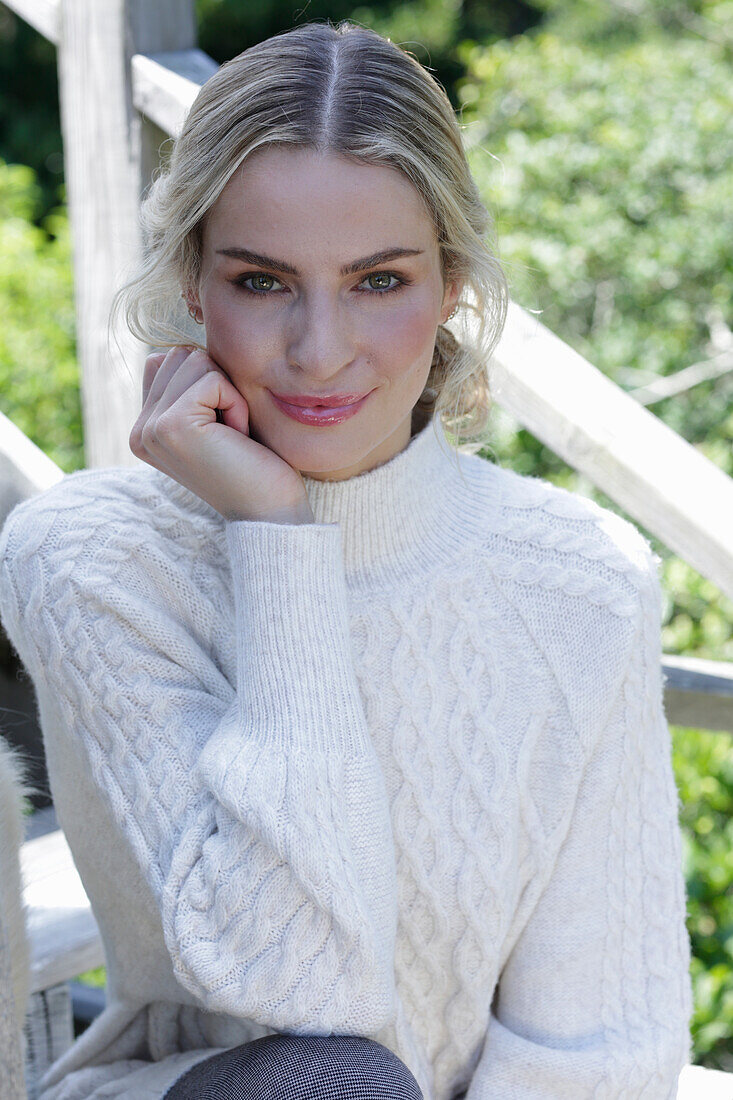 Junge blonde Frau in weißem Strickpullover