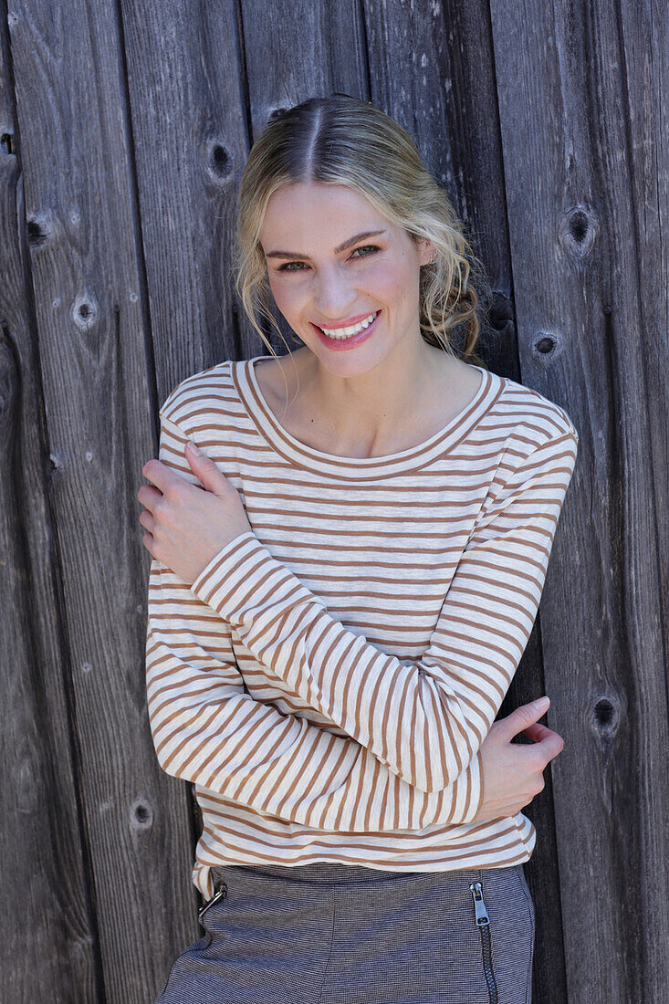 Young blond woman in striped shirt in front of board wall