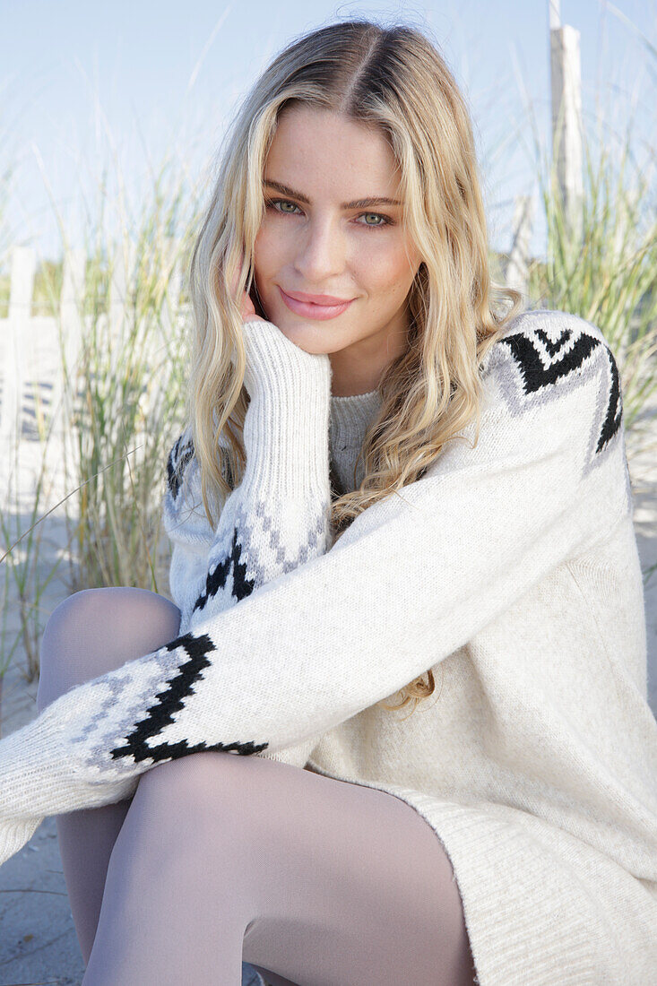 Young blond woman in light-coloured knitted dress with Norwegian pattern