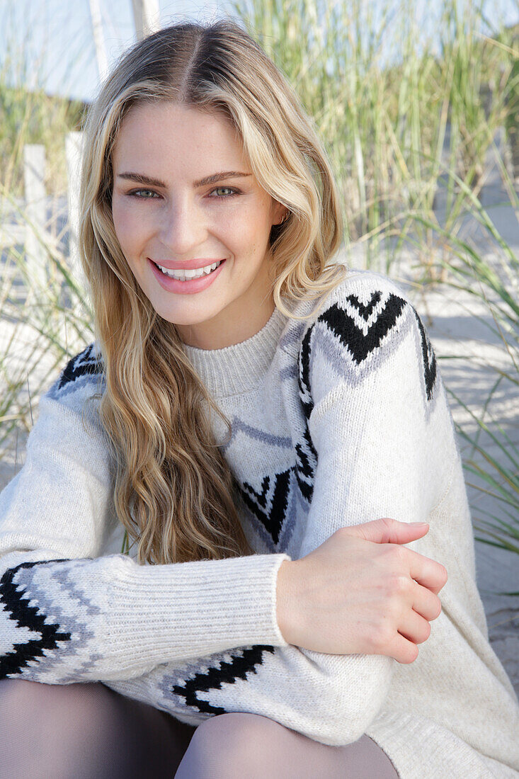 Young blond woman in light-coloured knitted dress with Norwegian pattern