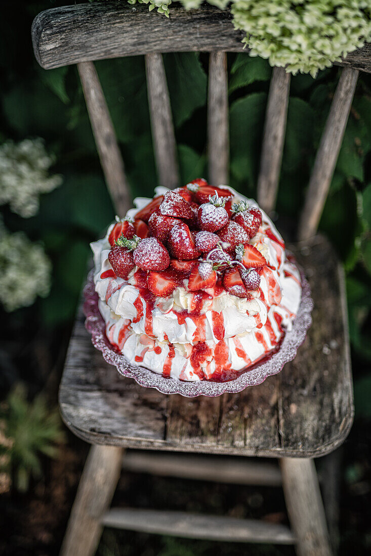 Baisertorte mit Erdbeeren auf rustikalem Holzstuhl