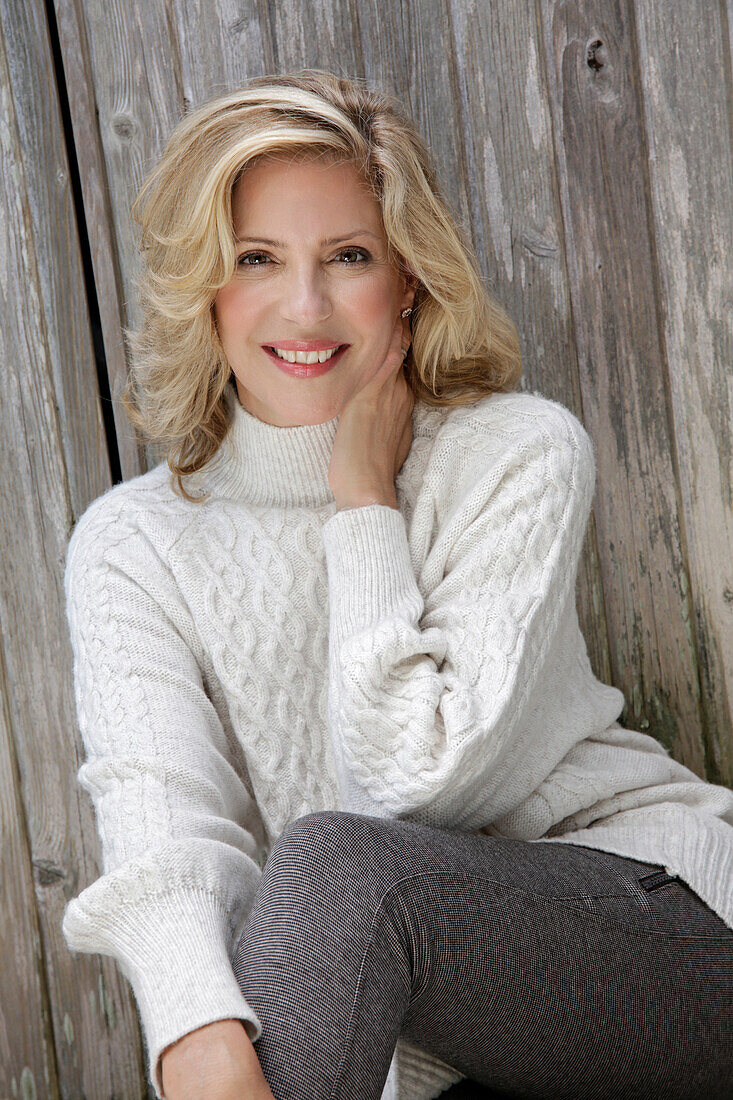 Mature blonde woman in white knitted jumper and grey leggings