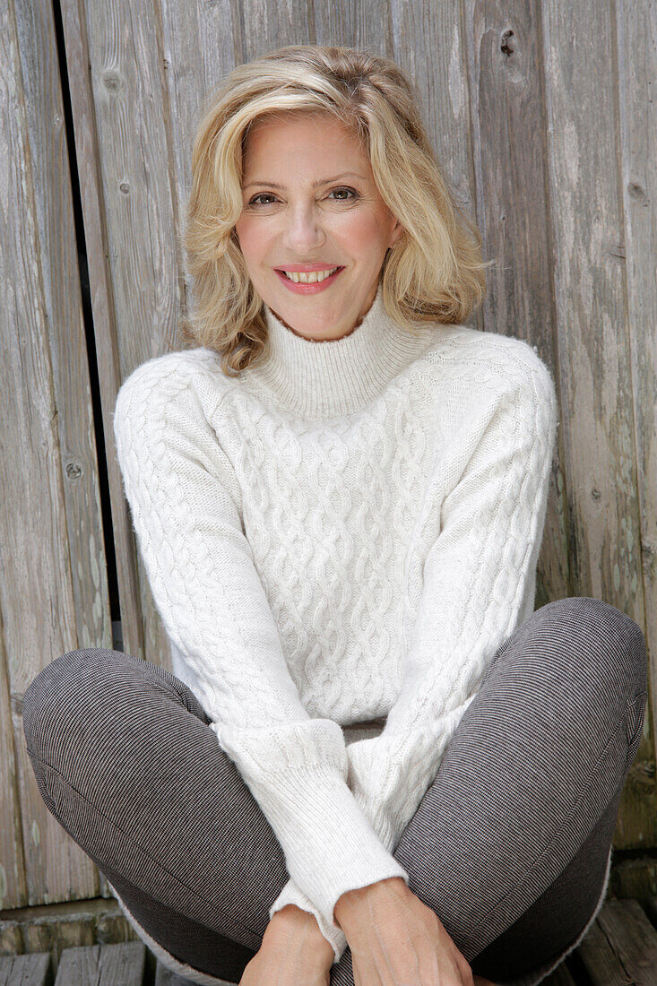 Mature blonde woman in white knitted jumper and grey leggings