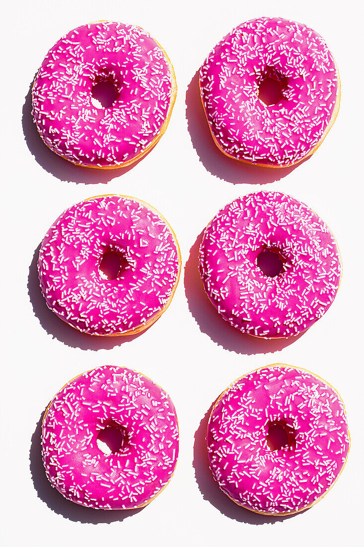 Doughnuts mit rosa Zuckerglasur auf weißem Untergrund