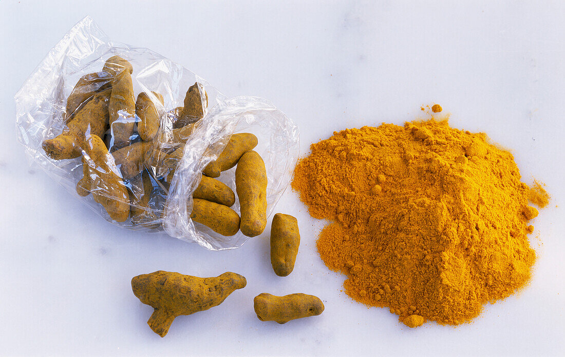 Cellophane bag with dried turmeric and ground turmeric on a light background
