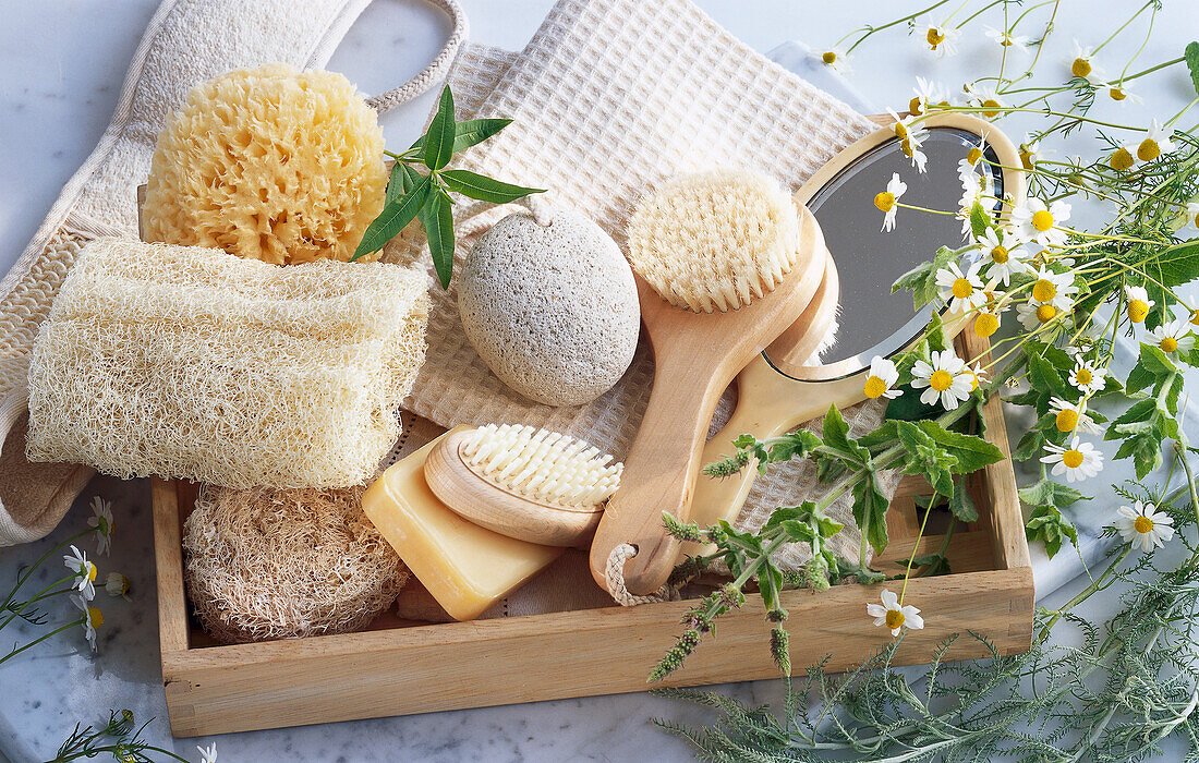 Still life with wellness accessories: bath sponge, loofah, brushes, mirror, soaps, and a pumice stone