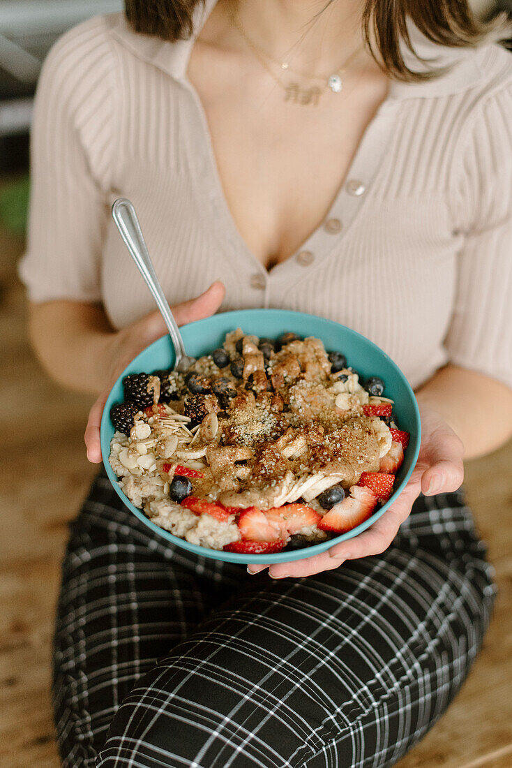 Junge Frau hält Schüssel mit Granola-Müsli in den Händen