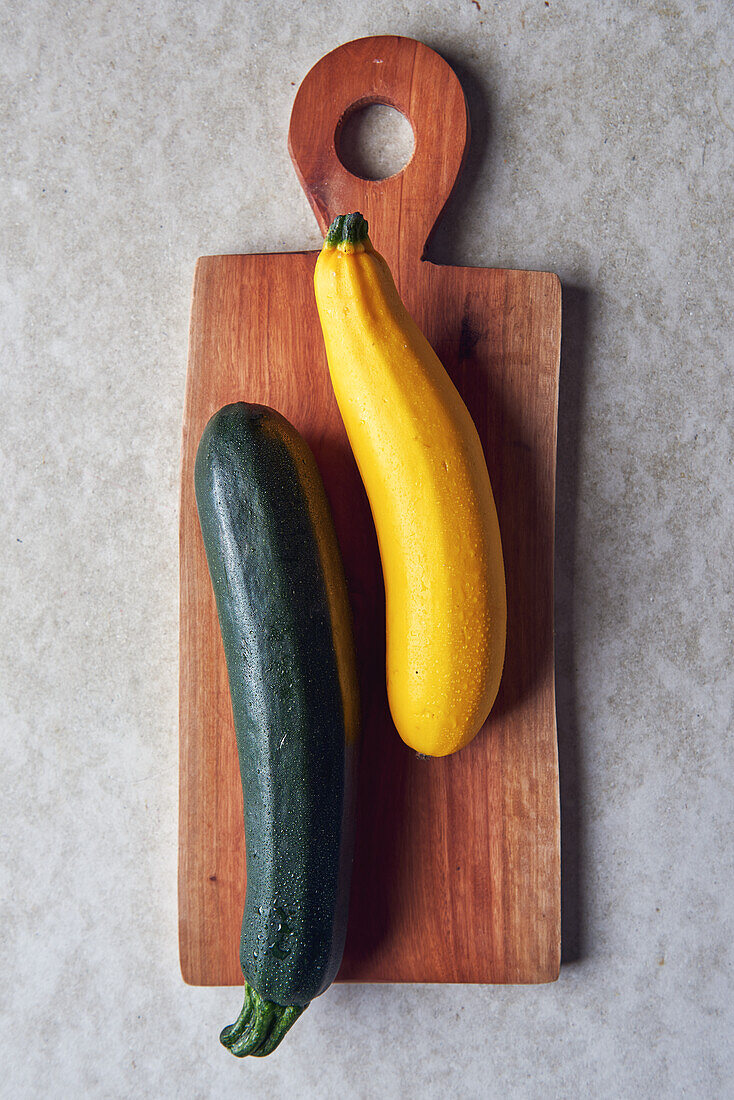 Gelbe und grüne Zucchini auf Holzbrett