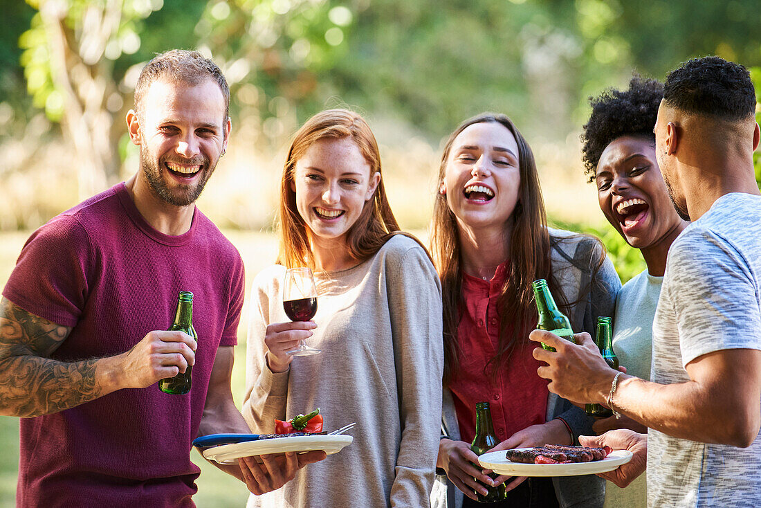 Happy young friends having food and drink in park