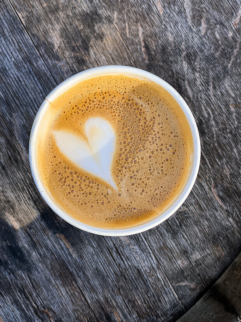 Flat White Coffee with heart decoration in a paper cup to go