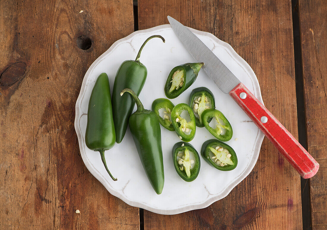 Jalapenos, whole and in rings with a knife on a plate