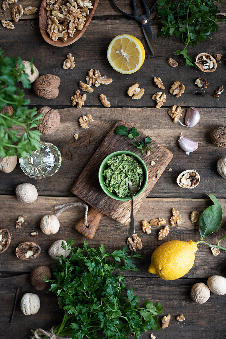 Parsley pesto and ingredients used in the pereparation on a wooden surface