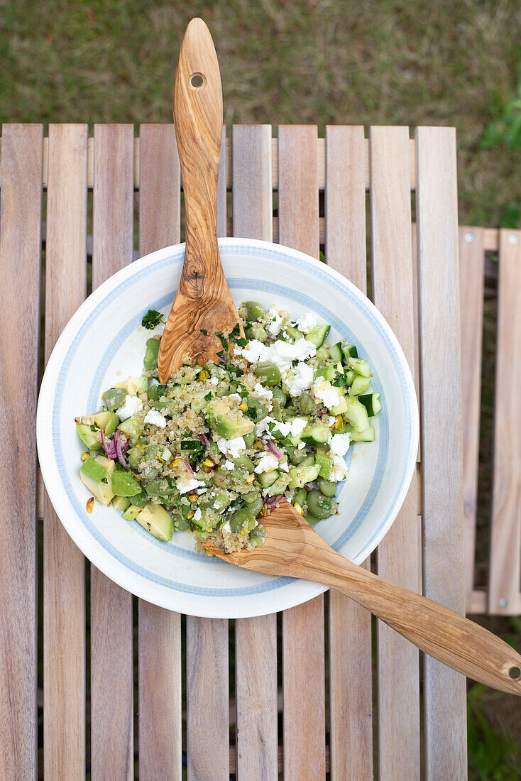 Fit summer salad made with broad beans, quinoa, avocado, cucumber, feta cheese, red onion, pistachios and mint