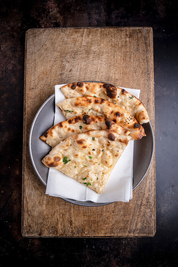 Knoblauch-Naan auf Holzbrett (Indien)