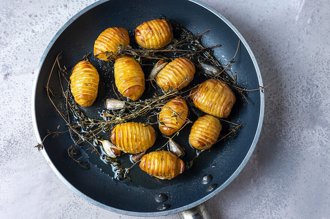 Roast hasselback potatoes in olive oil with thyme and garlic