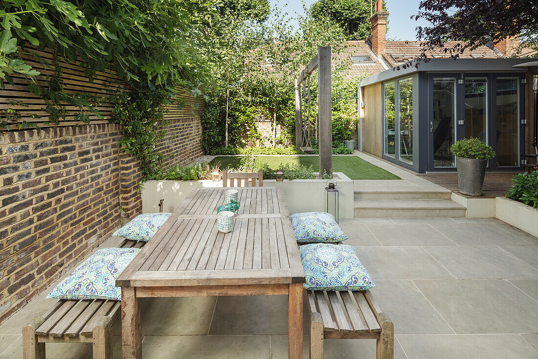 Wooden table with benches in front of brick wall on terrace