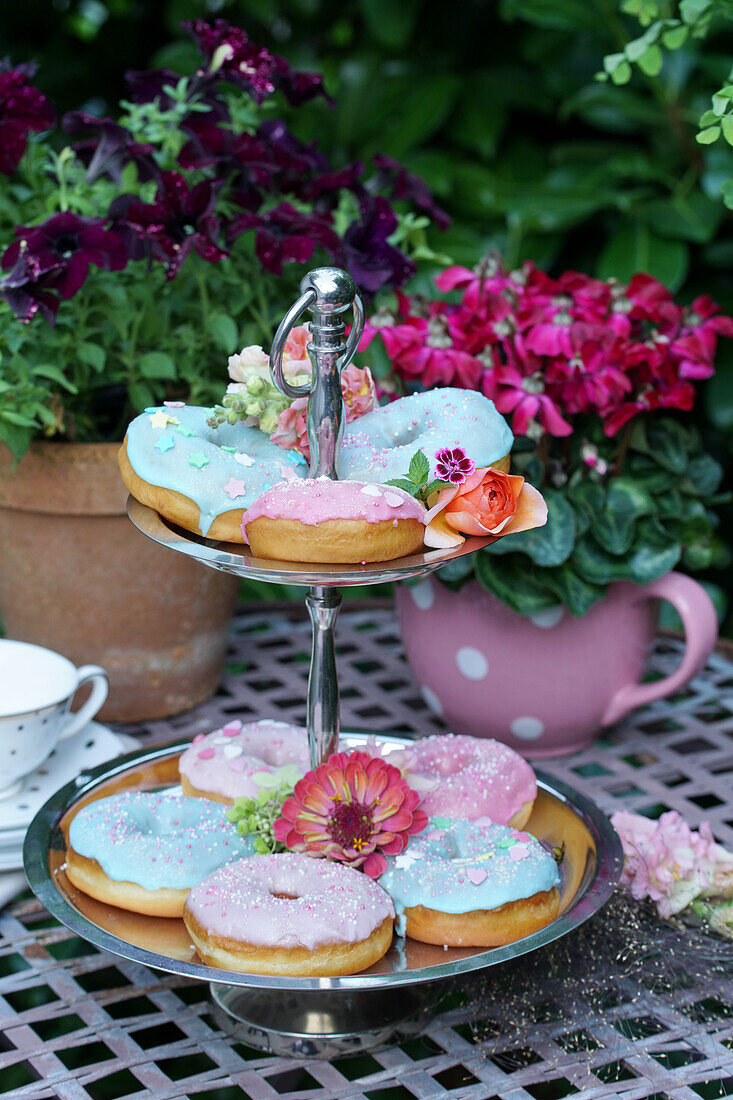 Donuts with pastel-coloured icing on a cake stand