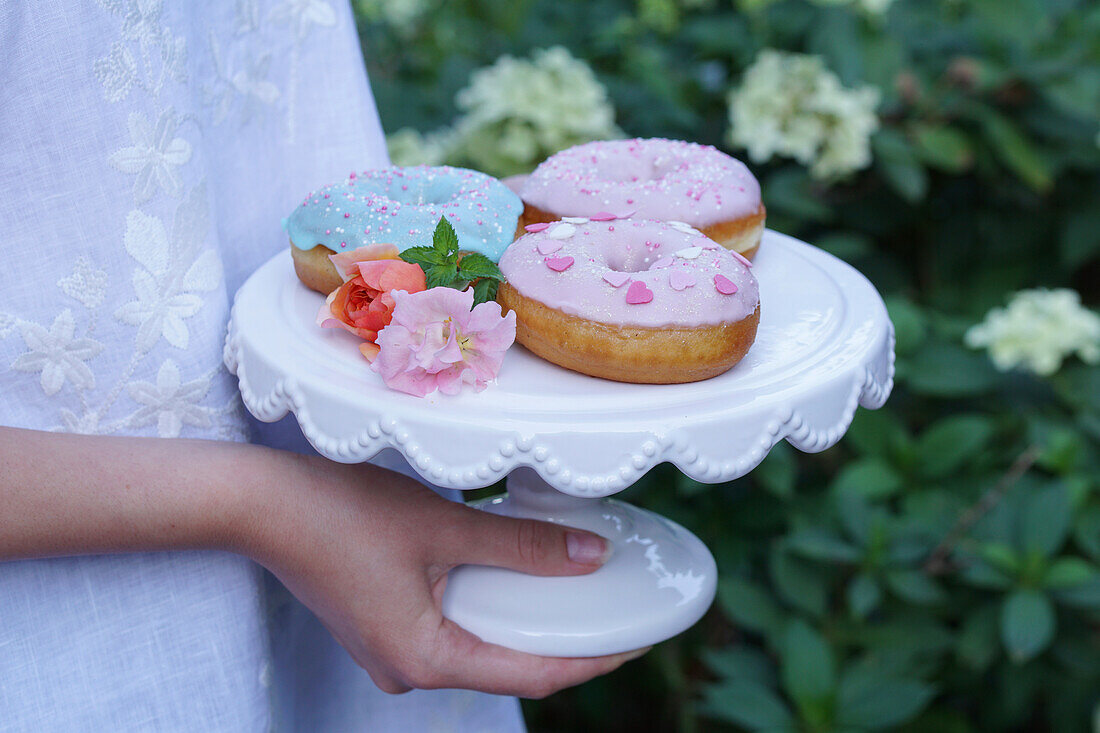 Donuts mit pastellfarbener Zuckerglasur auf Gebäckständer