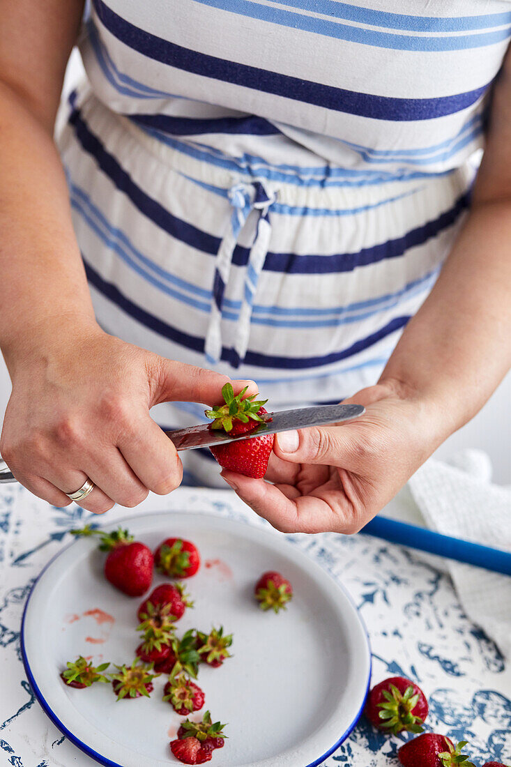Removing the tops from clean fresh strawberries for jam