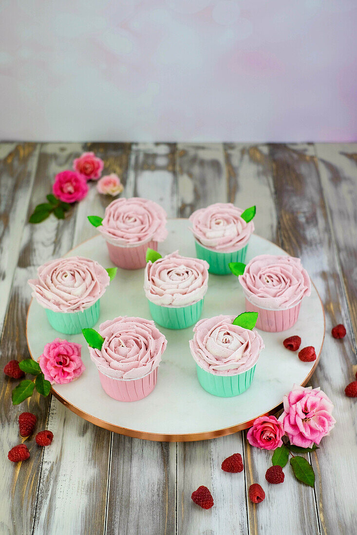 Raspberry cupcakes with pink cream frosting piped in a rose shape