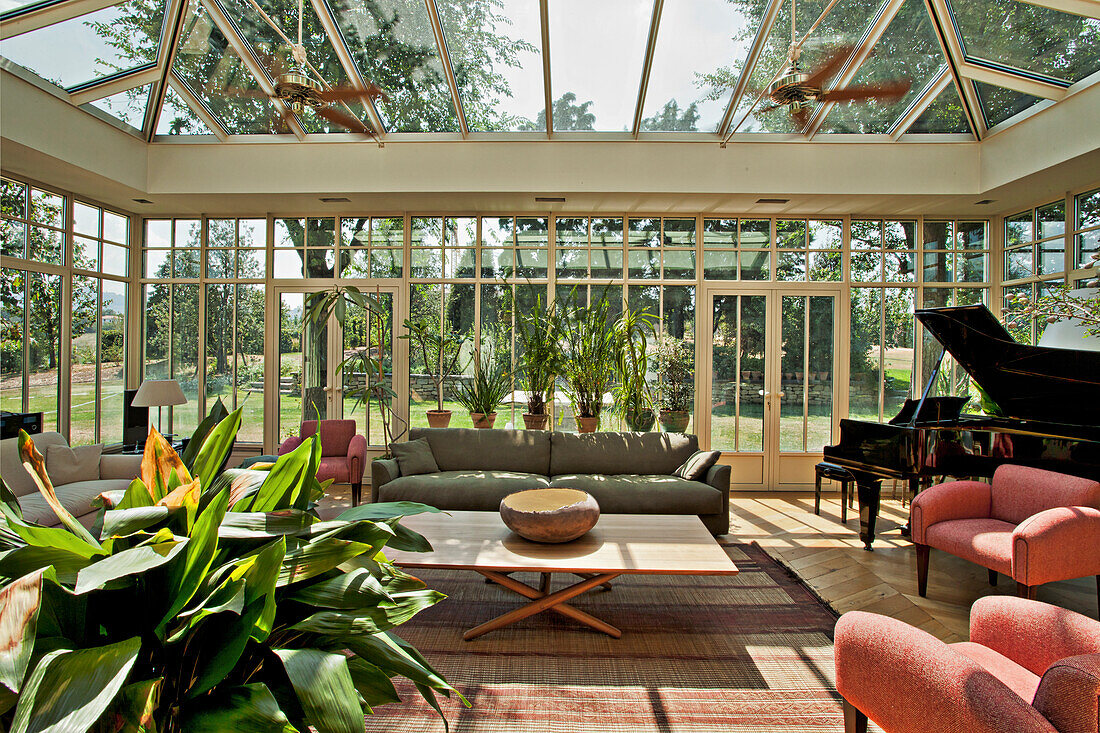 Sunny winter garden with seating furniture, potted plants, and piano