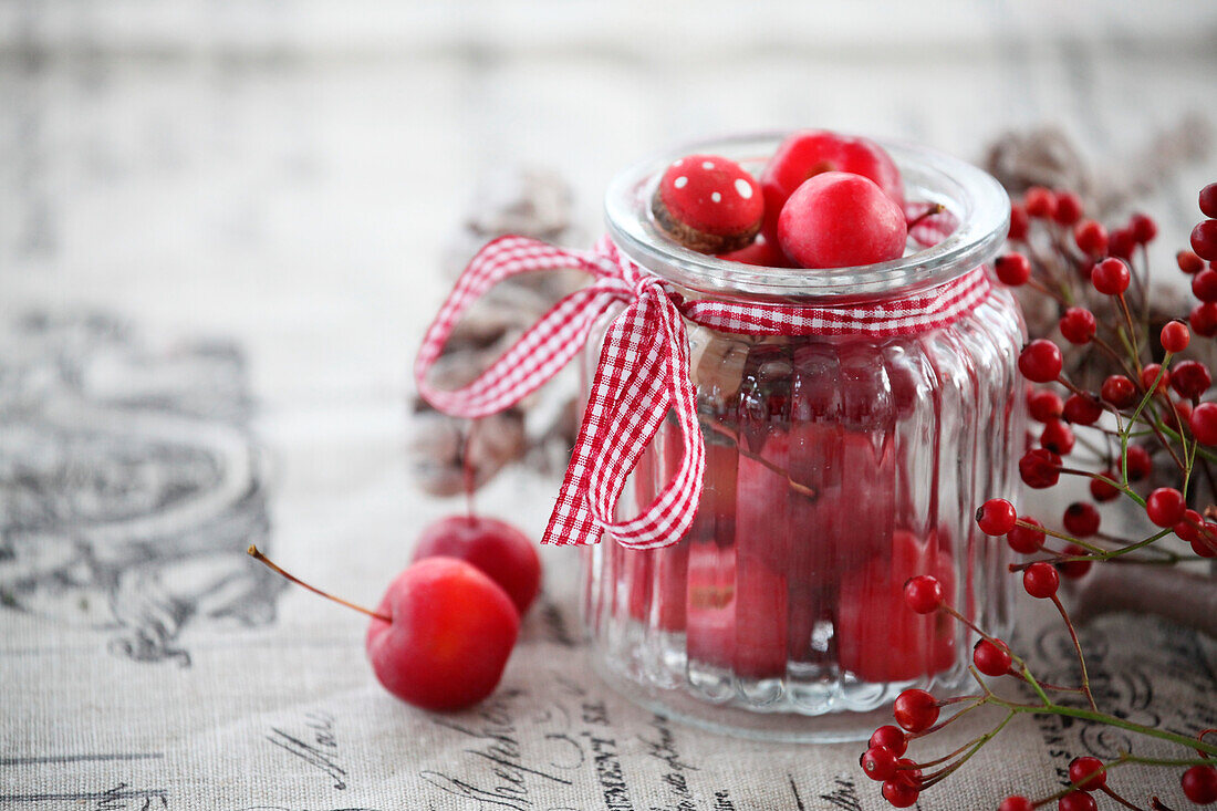 Decoration in a glass with ornamental apples and rose hips