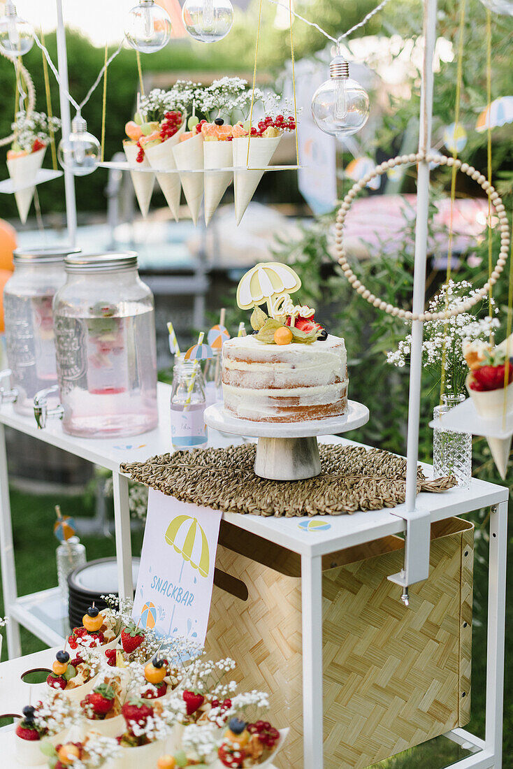 Party buffet with lemonade, naked cake and snack bags in the garden