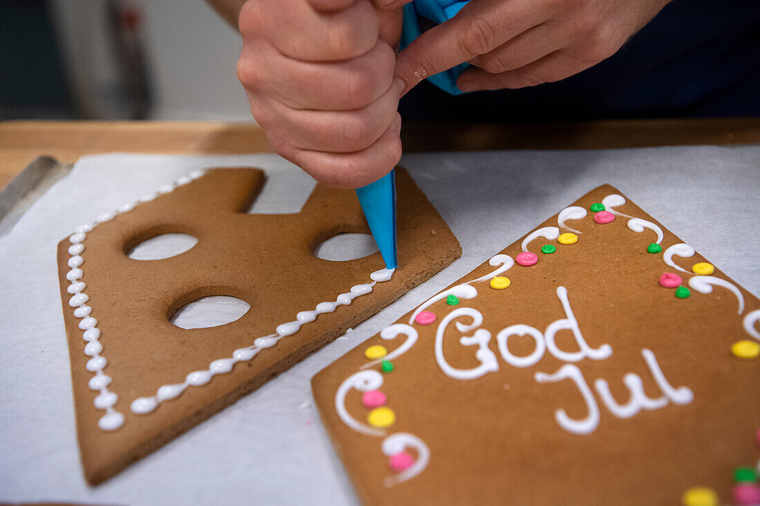 Decorating a gingerbread house with piping bag and icing