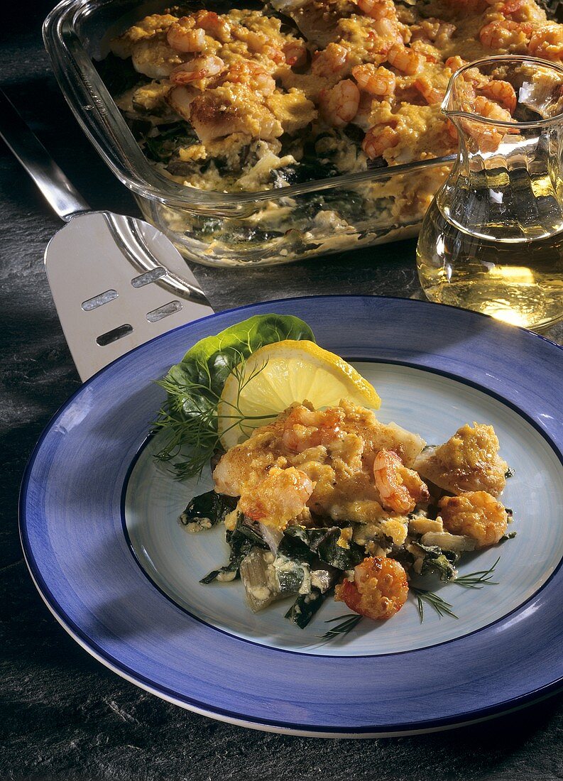 Cod gratin on chard with shrimps on plate and in dish