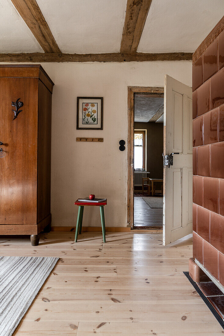 Wooden wardrobe in country bedroom with exposed wooden beams, tiled stove in the foreground