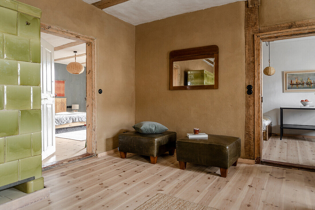 Green tiled stove and ottoman in a rustic room in neutral tones