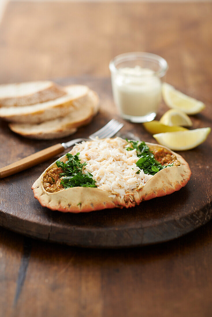 Edible crab served with bread, dip, and lemon wedges on wooden board