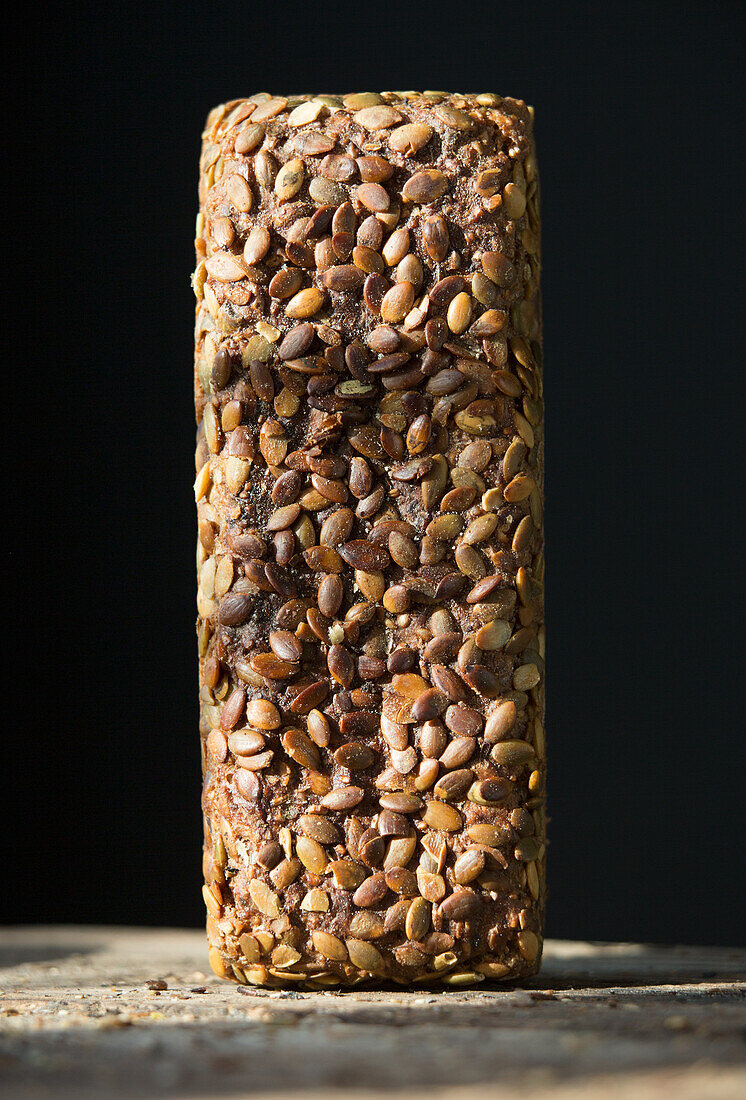 Boxed wholemeal bread with pumpkin seeds against a black background