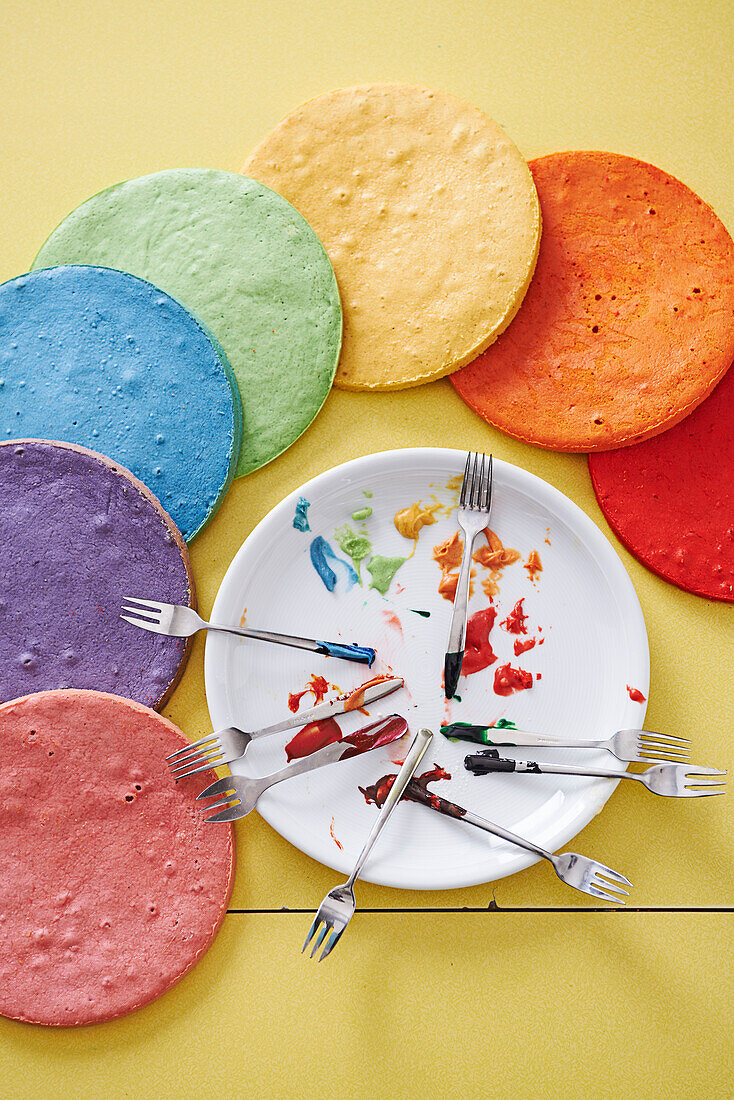 Regenbogenfarbene Tortenböden mit Lebensmittelfarben auf Teller