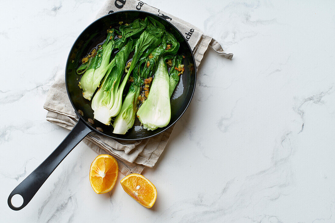 Asian cabbage bok choy braisd with garlic and citrus juice on marble table close up