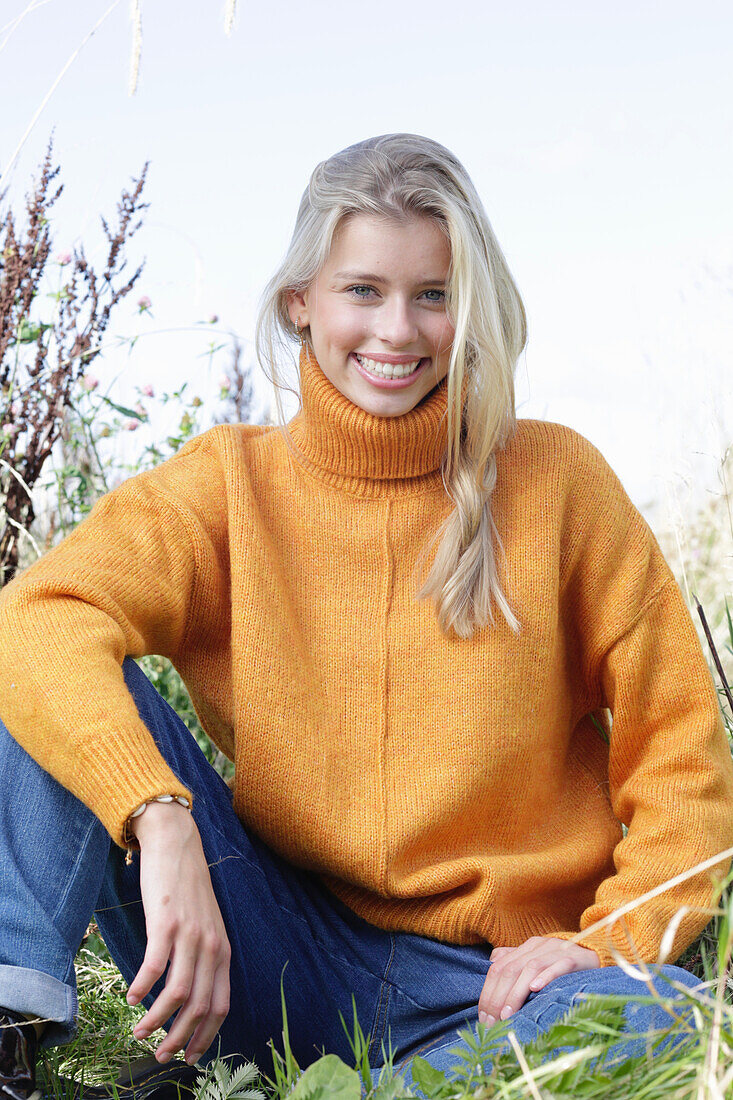 Young blonde woman in yellow turtleneck and jeans in nature