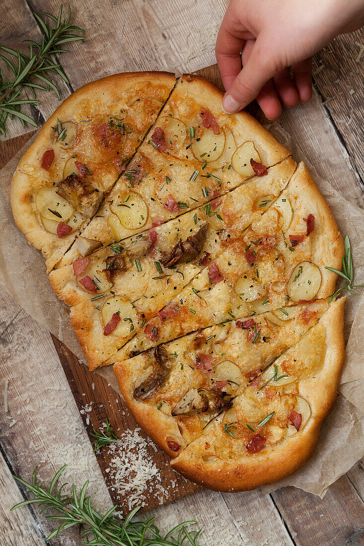 A white pizza cut into slices with a person taking a piece