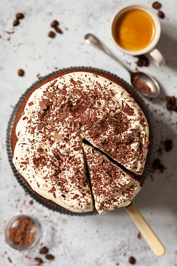 An Irish Coffee Cake with whipped cream and grated chocolate. A slice has been cut and is ready to serve.